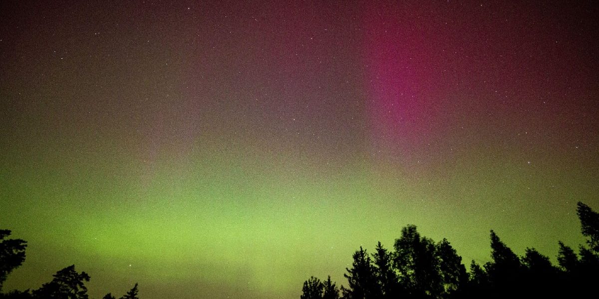 O auroră boreală în care se observă culorile verde și roz